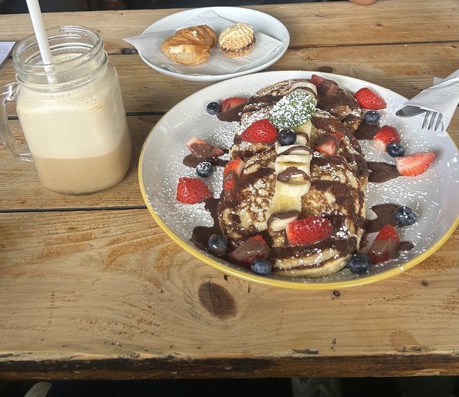 Loaded pancakes and a milkshake on a picnic bench